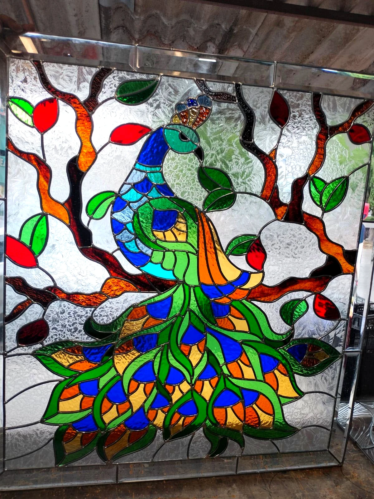 Vitral de un pavo real entre ramas