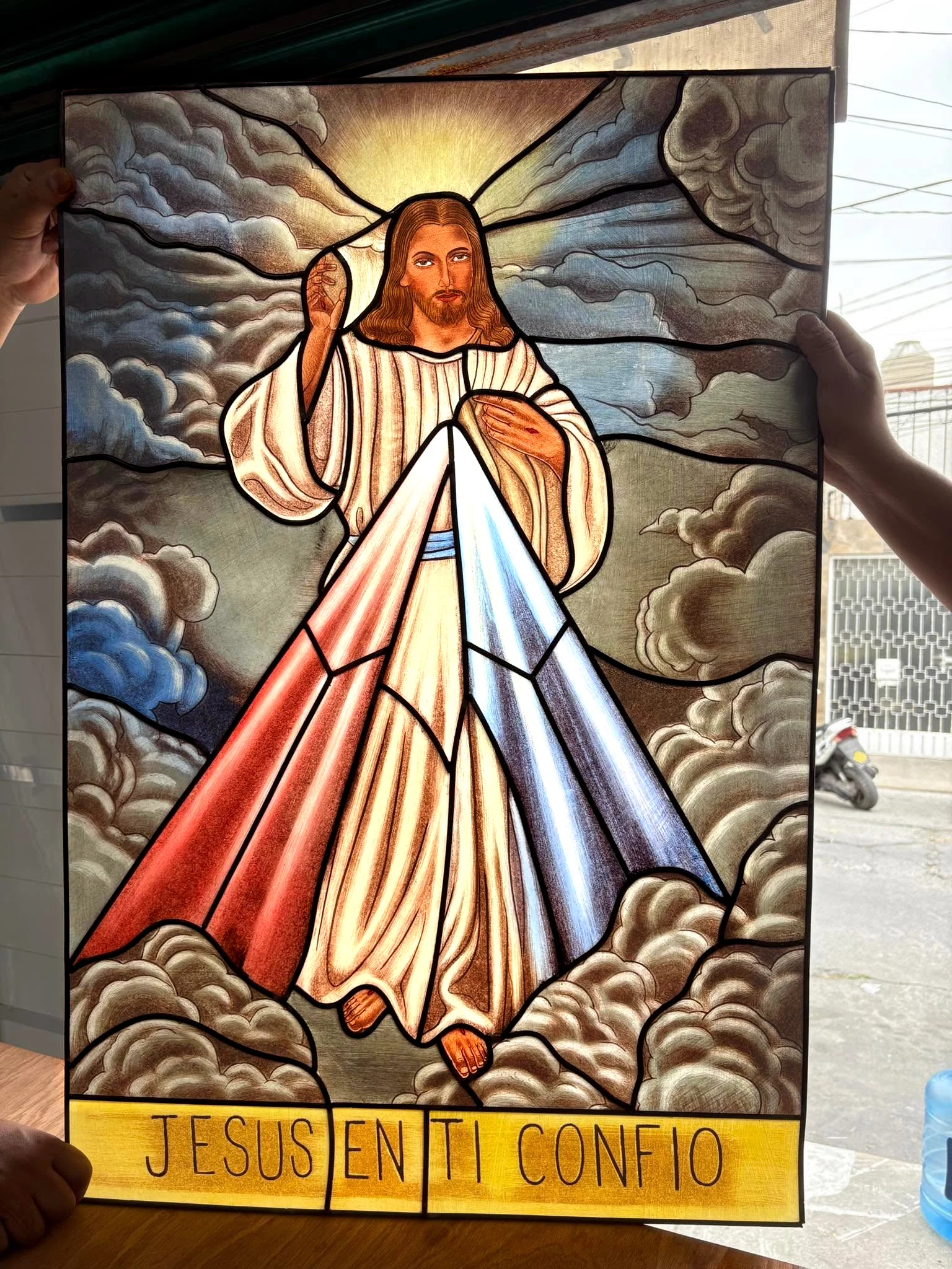 Vitral de Jesús con los brazos abiertos entre nubes