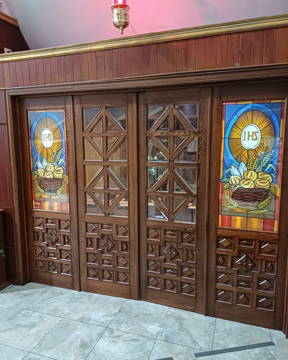 Puertas de madera con vitrales de símbolos eucarísticos